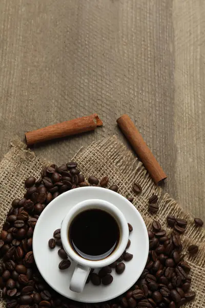 Siyah arka planda bir fincan kahve ve kahve çekirdeği..