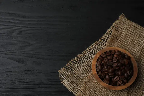 Koyu ahşap zemin üzerinde kavrulmuş kahve çekirdekleri ve metin için kopyalama alanı