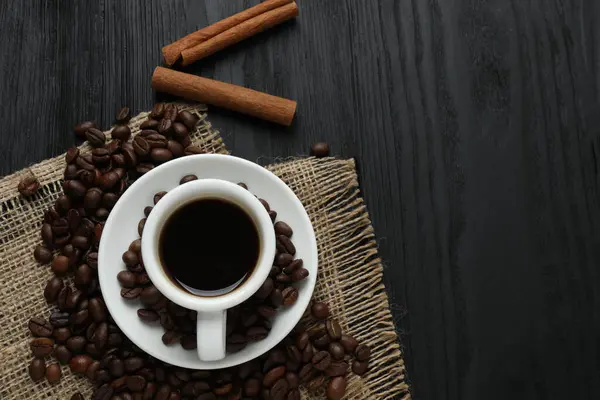 Tarçın çubuklu bir fincan kahve ve ahşap arka planda anason.