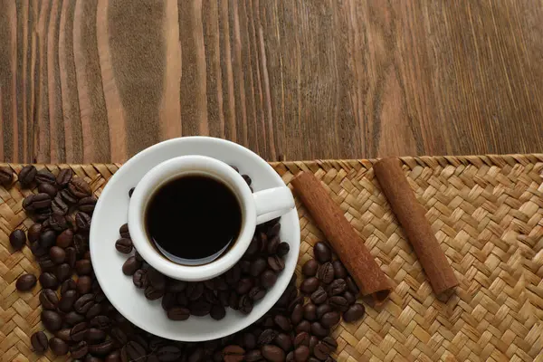 Bir fincan kahve, tarçın ve tahtadan arka planda kahve taneleri..