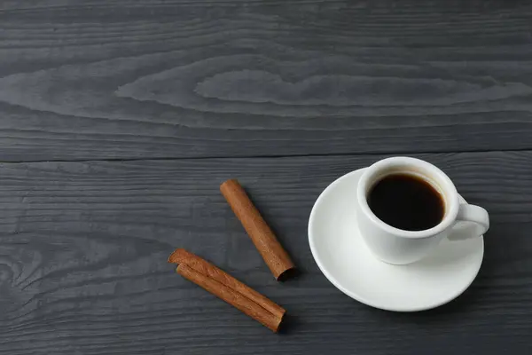 Bir fincan kahve, tarçın çubukları ve tahta bir tahta üzerinde anason çubukları, beyaz ahşap arka planda. en üstteki görünüm