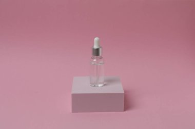 Pembe arka planda damlatıcısı olan bir şişe. güzellik ve kozmetik.