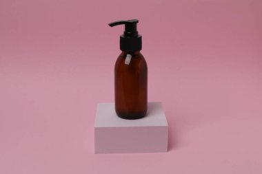 Pembe arka planda etiketli bir şampuan şişesi.