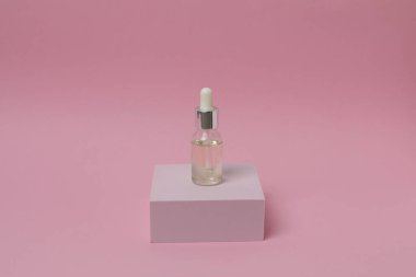 Pembe arka planda pipeti olan serum şişesi. minimalizm.