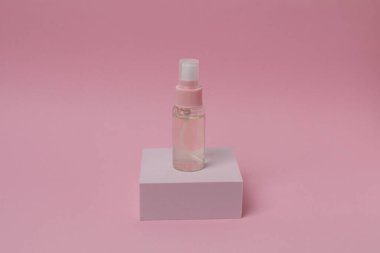 Pembe pastel arka planda bir şişede parfüm.