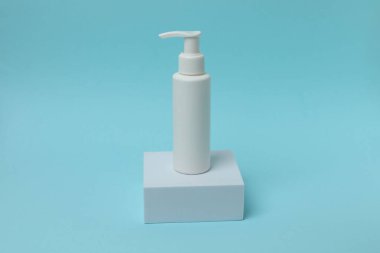 Fotokopi alanı olan mavi arkaplanda boş etiketli kozmetik şişe.