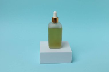 Açık bej arka planda bir şişe serum ya da yüz yağı