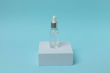 bir şişe serum ya da yüz ve yüz için pipet mavi arka planda bir pipetle.