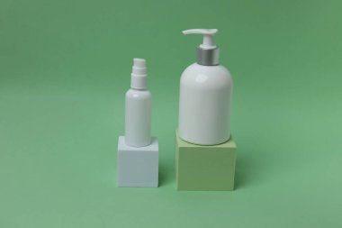 iki şişe kozmetik krem ya da losyon, krem ya da losyon, bej arka planda şişe ve yeşil yapraklar.