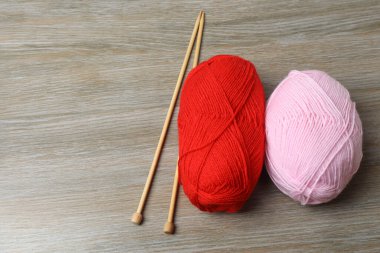 Ahşap masaya iğneler ve iğnelerle örgü örmek için renkli iplikler, yakın plan.