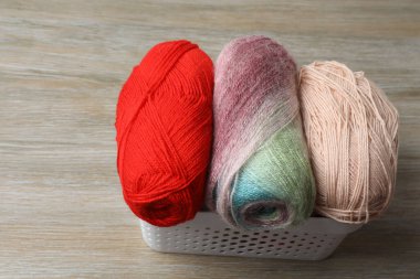 Gri arka plana karşı beyaz masada örgü iğneleri olan sepet.