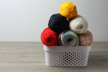 farklı renklerde örgü topları ve ahşap masa üzerinde örgü iğneleri, metin için alan