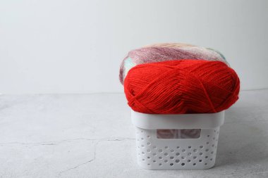 Kırmızı ve beyaz örgü bir şapka ve gri arka planda örgü örmek için bir iplik..