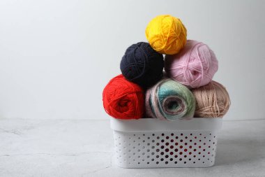 Masada farklı iplik topları olan bir sepet.