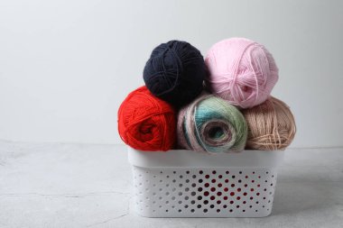 Beyaz tuğla duvara karşı gri masanın üzerinde farklı örgü iğneleri olan sepet, metin için alan