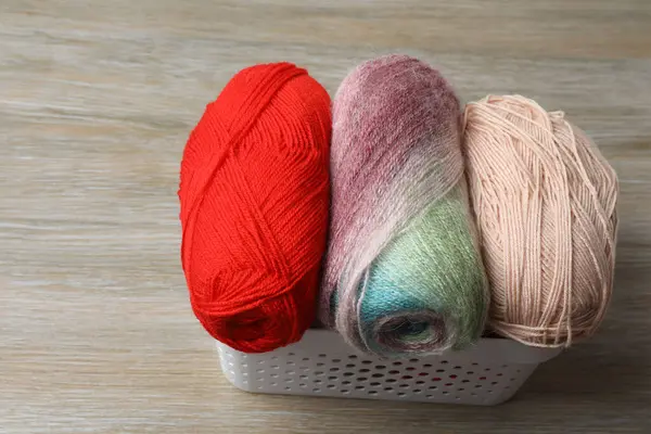 Gri arka plana karşı beyaz masada örgü iğneleri olan sepet.