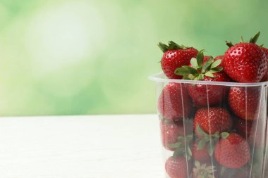 Konteynırdaki ahşap masada çilekler.