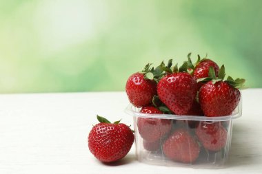 Konteynırdaki ahşap masada çilekler.