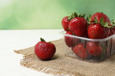 Konteynırdaki ahşap masada çilekler.