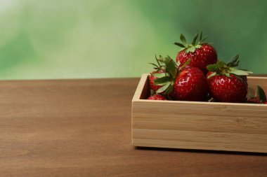 Konteynırdaki ahşap masada çilekler.