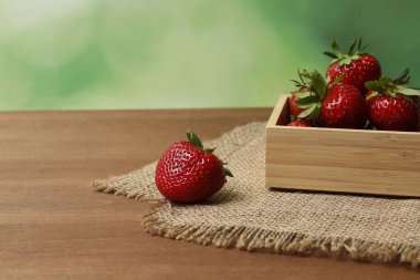 Konteynırdaki ahşap masada çilekler.