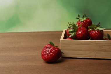 Konteynırdaki ahşap masada çilekler.