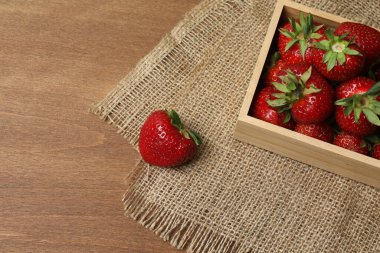 Konteynırdaki ahşap masada çilekler.