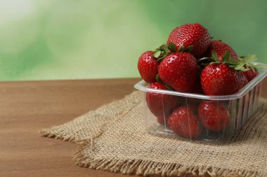 Konteynırdaki ahşap masada çilekler.