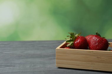 Konteynırdaki ahşap masada çilekler.