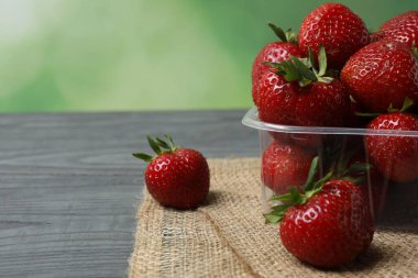 Konteynırdaki ahşap masada çilekler.