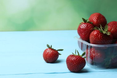 Konteynırdaki ahşap masada çilekler.