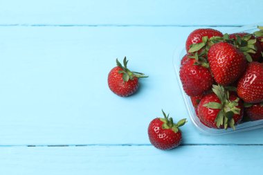 Konteynırdaki ahşap masada çilekler.