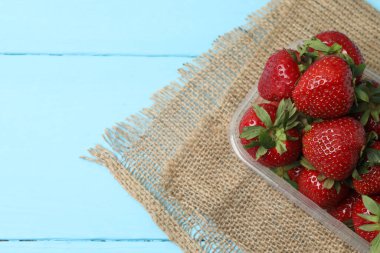 Konteynırdaki ahşap masada çilekler.