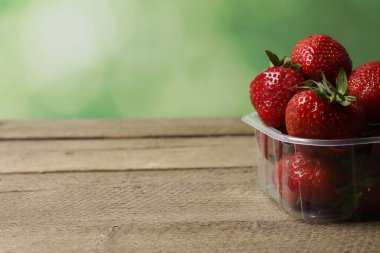 Konteynırdaki ahşap masada çilekler.