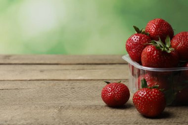 Konteynırdaki ahşap masada çilekler.