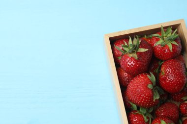 Konteynırdaki ahşap masada çilekler.