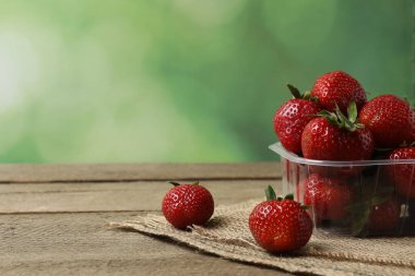 Konteynırdaki ahşap masada çilekler.