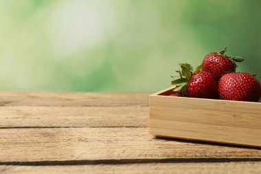 Konteynırdaki ahşap masada çilekler.