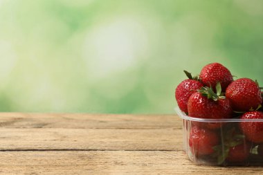 Konteynırdaki ahşap masada çilekler.