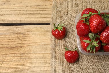 Konteynırdaki ahşap masada çilekler.