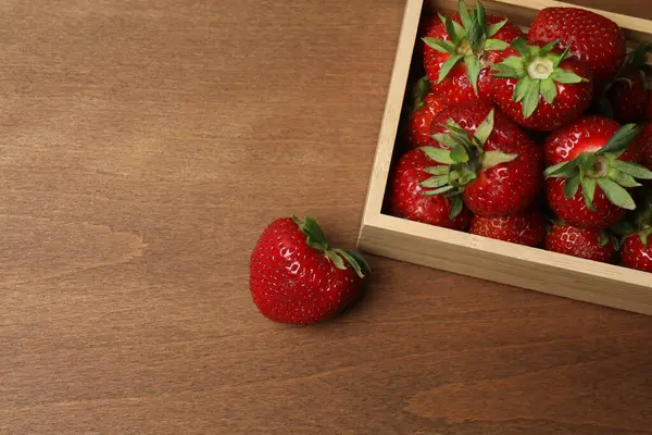 Konteynırdaki ahşap masada çilekler.