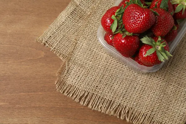 Konteynırdaki ahşap masada çilekler.