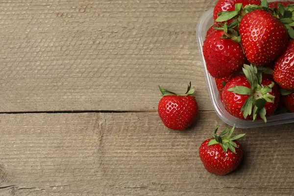 Konteynırdaki ahşap masada çilekler.