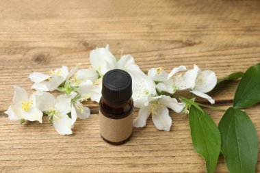 Tıbbi ve kozmetik kullanım için indirme şişeleri ve ahşap masada yasemin çiçekleri. Doğal kozmetik ürünleri ve temel eko-ambalaj, spa konsepti.