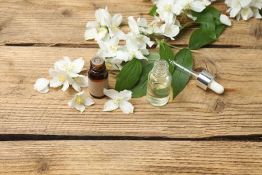 Tıbbi ve kozmetik kullanım için indirme şişeleri ve ahşap masada yasemin çiçekleri. Doğal kozmetik ürünleri ve temel eko-ambalaj, spa konsepti.