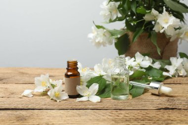 Tıbbi ve kozmetik kullanım için indirme şişeleri ve ahşap masada yasemin çiçekleri. Doğal kozmetik ürünleri ve temel eko-ambalaj, spa konsepti.