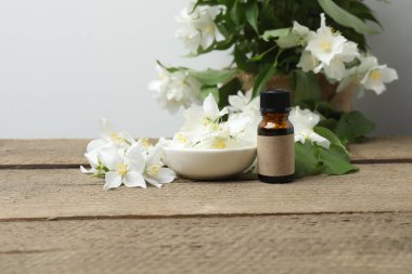 Tıbbi ve kozmetik kullanım için indirme şişeleri ve ahşap masada yasemin çiçekleri. Doğal kozmetik ürünleri ve temel eko-ambalaj, spa konsepti.