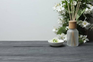 Tıbbi ve kozmetik kullanım için indirme şişeleri ve ahşap masada yasemin çiçekleri. Doğal kozmetik ürünleri ve temel eko-ambalaj, spa konsepti.