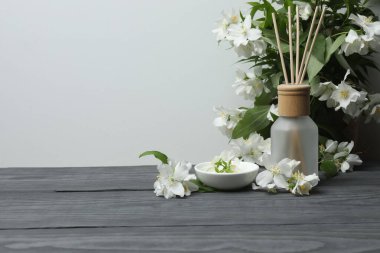 Tıbbi ve kozmetik kullanım için indirme şişeleri ve ahşap masada yasemin çiçekleri. Doğal kozmetik ürünleri ve temel eko-ambalaj, spa konsepti.