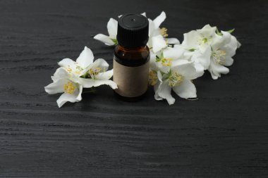 Tıbbi ve kozmetik kullanım için indirme şişeleri ve ahşap masada yasemin çiçekleri. Doğal kozmetik ürünleri ve temel eko-ambalaj, spa konsepti.